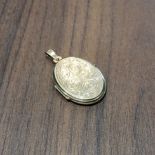 A 9ct gold oval locket, scroll decoration to front, 3.24g gross