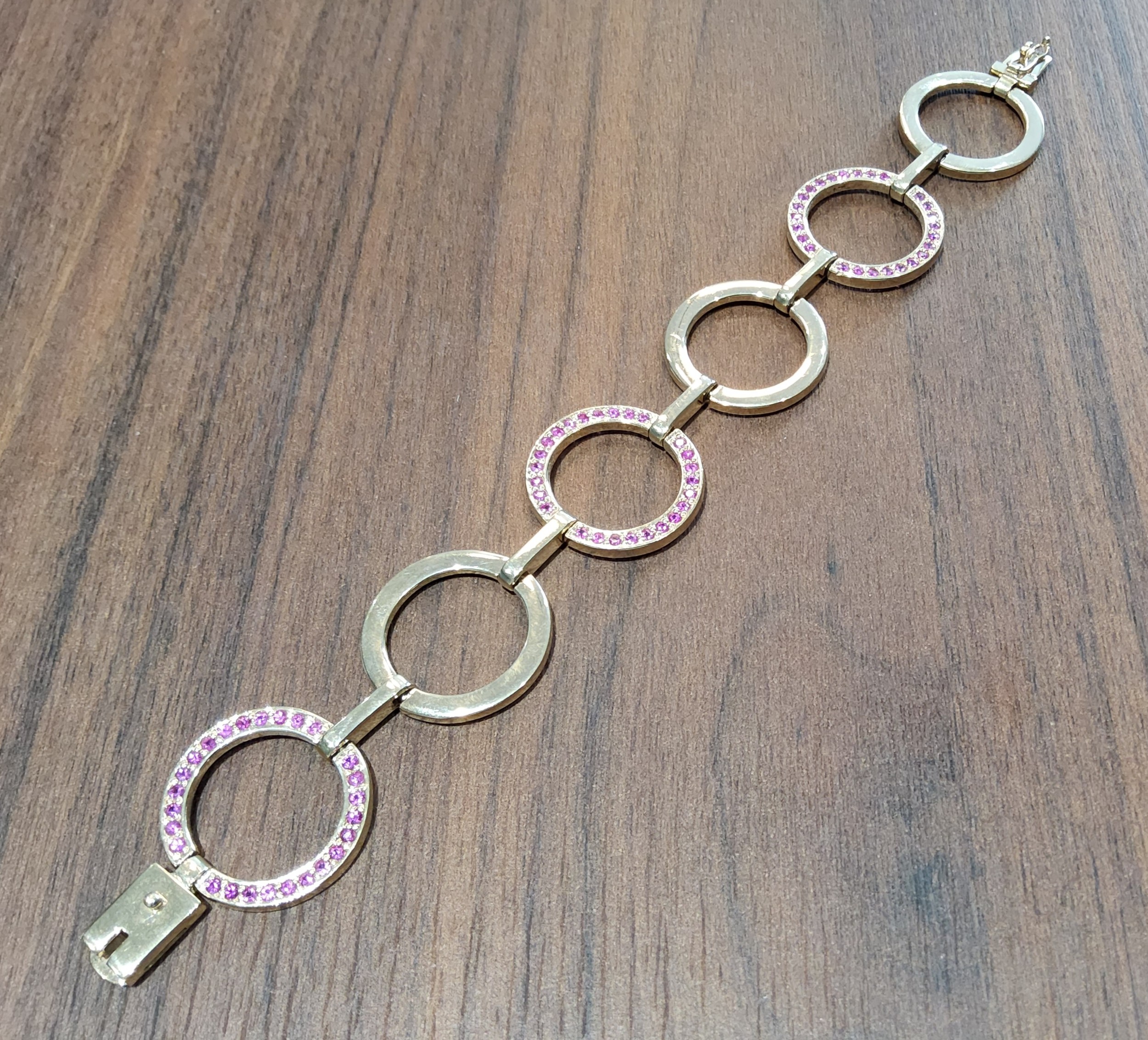 A contemporary 9ct gold fancy link bracelet, each alternate circular link set with round pink