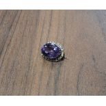 A Victorian yellow metal mounted halo brooch set with a central oval amethyst, surrounded by seed