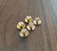 A set of five 9ct gold studs, two with enamel decoration, three with a machined chequer board design