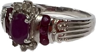 A 10ct white gold set with a central oval ruby flanked six round diamond chips, the two shoulders
