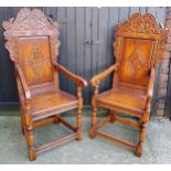 A pair of country house Wainscot type hall chairs, profusely carved head rest with bold lozenge