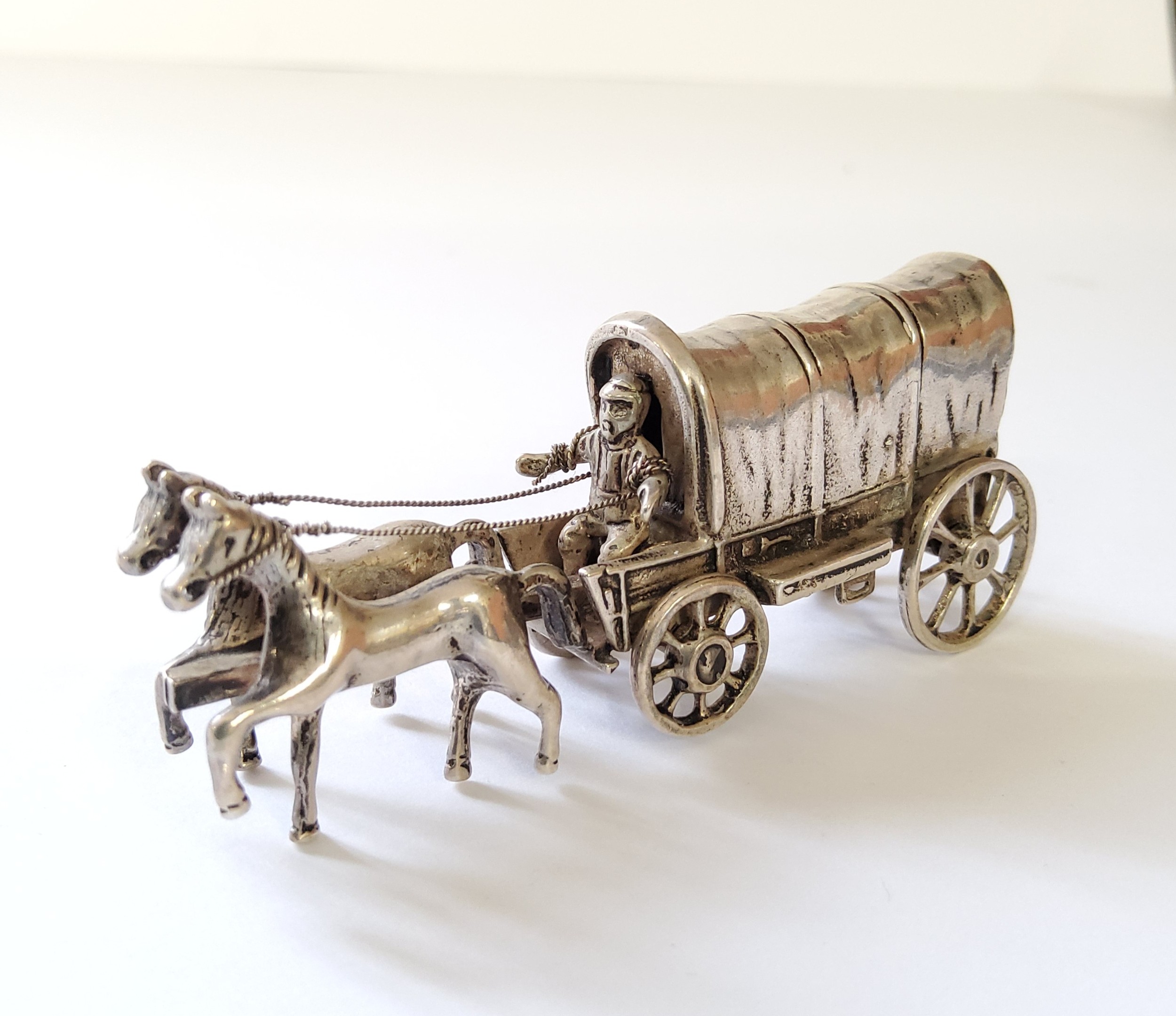 A continental white miniature of a horse drawn conestoga wagon with driver, indistinct marks 50.11g