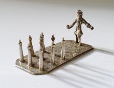 A Continental white metal miniature of a man playing street ninepins on a rectangular base