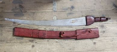 A large South African tribal sword in embossed red leather sheath, the curved blade etched with