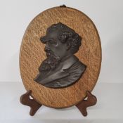 Charles Dickens - a bronze bust mounted on an oval oak plaque. 28cm high. Excellent condition.