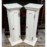 A pair of painted plinths with door to the body of the column, revealing shelves.