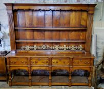 A large 20th century yew wood country kitchen dresser, the oversailing cornice above a three shelved