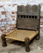 A 19th century Indian Pida Rajasthani low chair, the chip carved geometric panelled wooden back rest