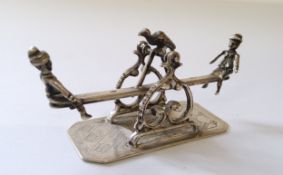 A Dutch silver miniature of two children on a see-saw, with bird percehd centrally, indistinct mark,