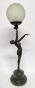 An Art Deco style bronzed lamp of a semi nude  figure, holding a textured glass globe aloft,