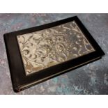 A silver mounted black leather guest book, the silver panel embossed in relief with Reynolds Angels,