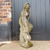 A reconstituted stone garden statue of a scantily clad lady bathing.