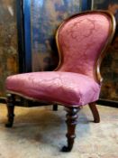 A Victorian nursing chair in a rich pink damask upholstery c.1860, brass castors
