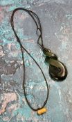 A Maori carved Pounamu pendant carved in the form of an infinity symbol on a cord necklace