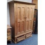 A farmhouse pine double wardrobe, ogee cornice over two fielded panelled doors, holding two short