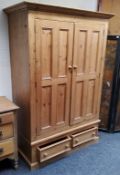 A farmhouse pine double wardrobe, ogee cornice over two fielded panelled doors, holding two short