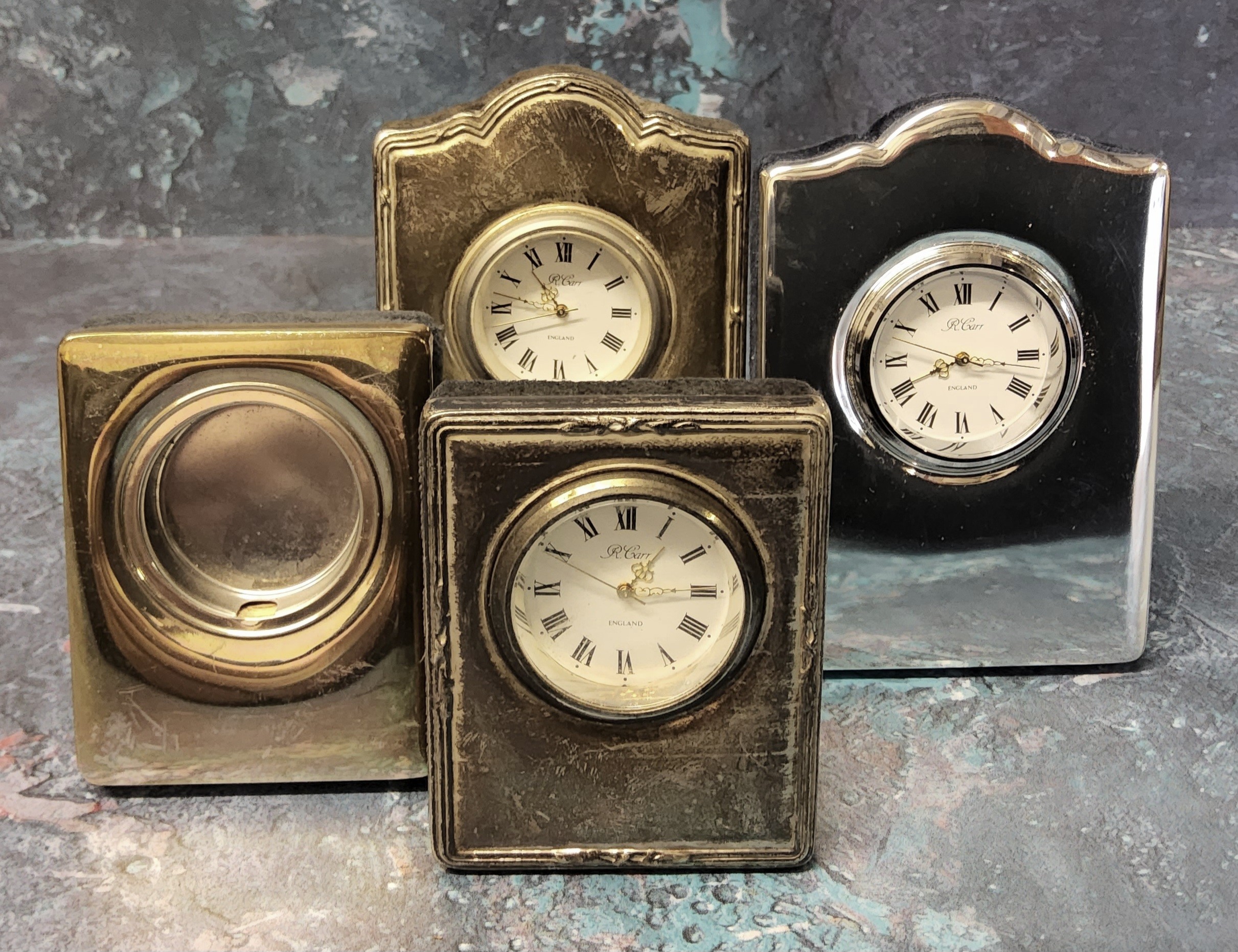 Two silver mounted miniature clocks in form of a mantel clock, velvet backed, an embosed and plain