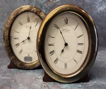 A pair of silver mounted oval clocks, plain silver panel, a vacant silver panel to rear, wood