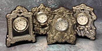 Three silver mounted miniature clocks in form of shaped mantel clocks, embossed silver panels to