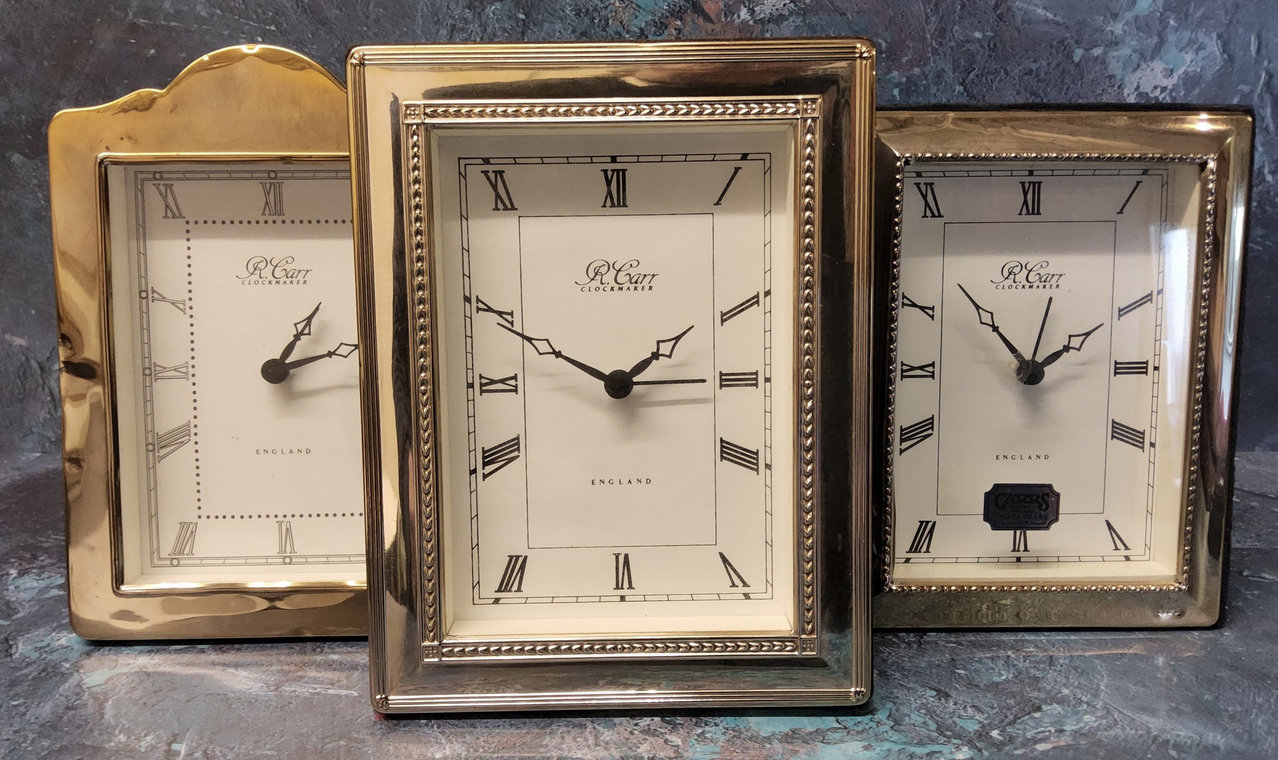 Three silver mounted alarm clocks, silver panel embossed in relief, one wood backed, two velvet