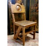An early 20th century oak Arts and Crafts metamorphic library chair/steps, the back with roundel,