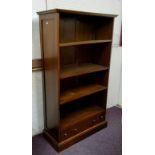 A modern hardwood open bookcase, oversailing cornice above four open shelves and one long and two