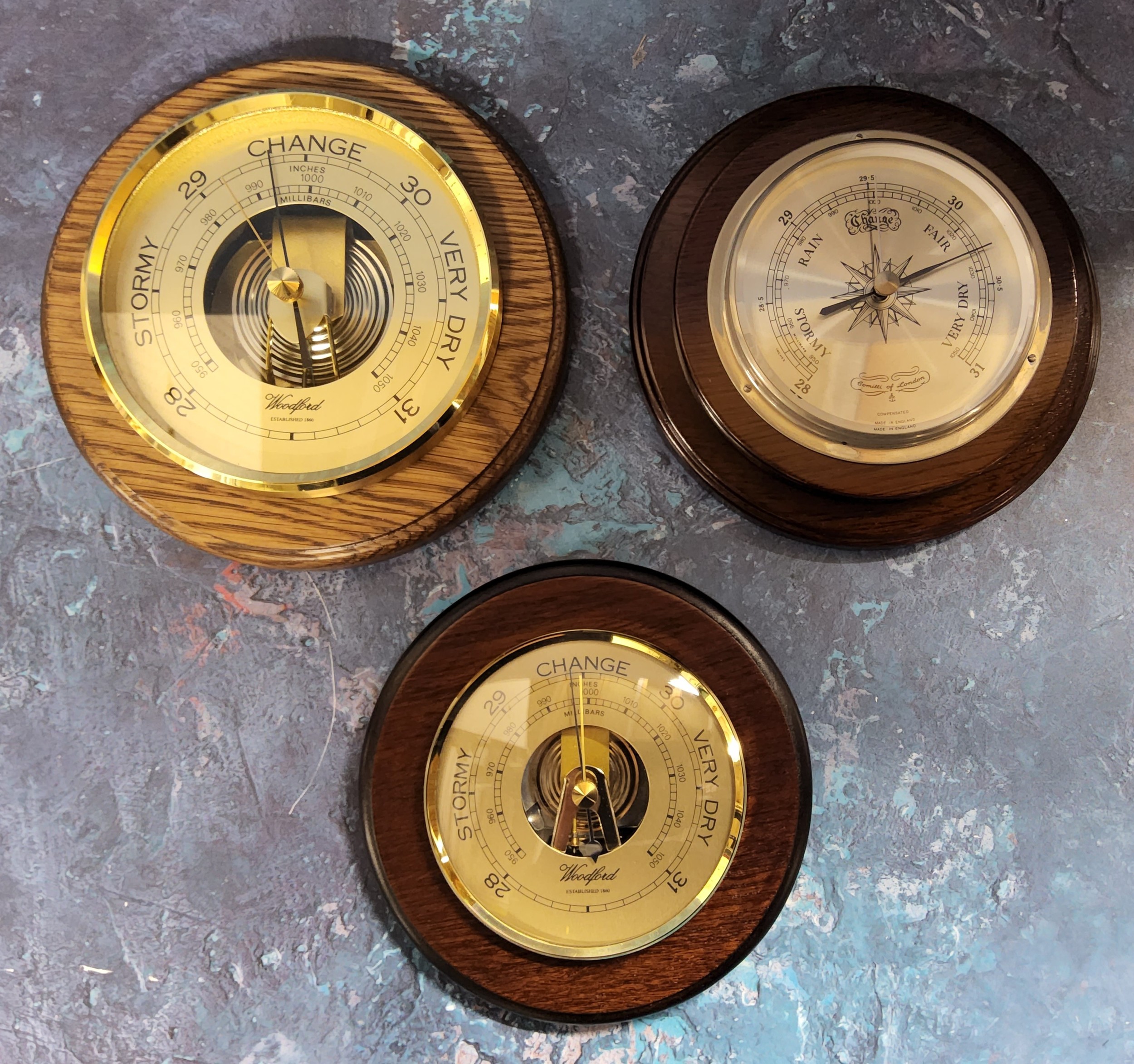 A Woodford oak mounted circular brass barometer, 17cms dia.; another brass & mahogany 15cms; a