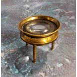 A Victorian brass map magnifying loupe raised on three shaped legs, adjustable magnifying lens