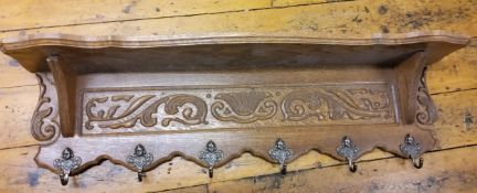 A mid 20th century oak coat hook and shelf, carved with scrolling foliage, 100cm long