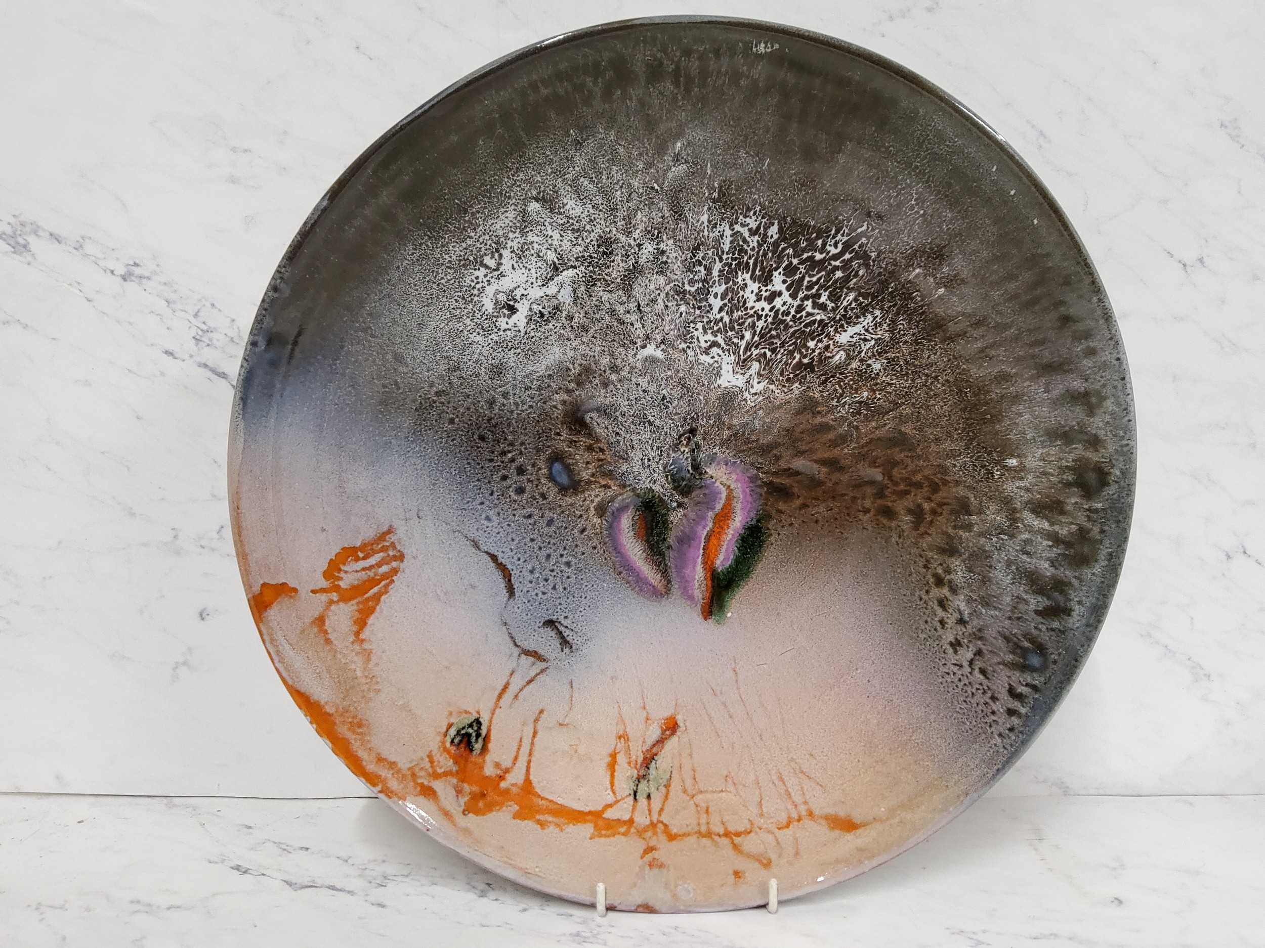 A Studio Pottery charger, decorated with a mottled dripped glaze, in orange, green, brown and white,
