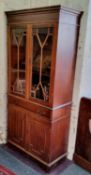 A Victorian style mahogany display cabinet, dental cornice above two glazed doors enclosing shelves,