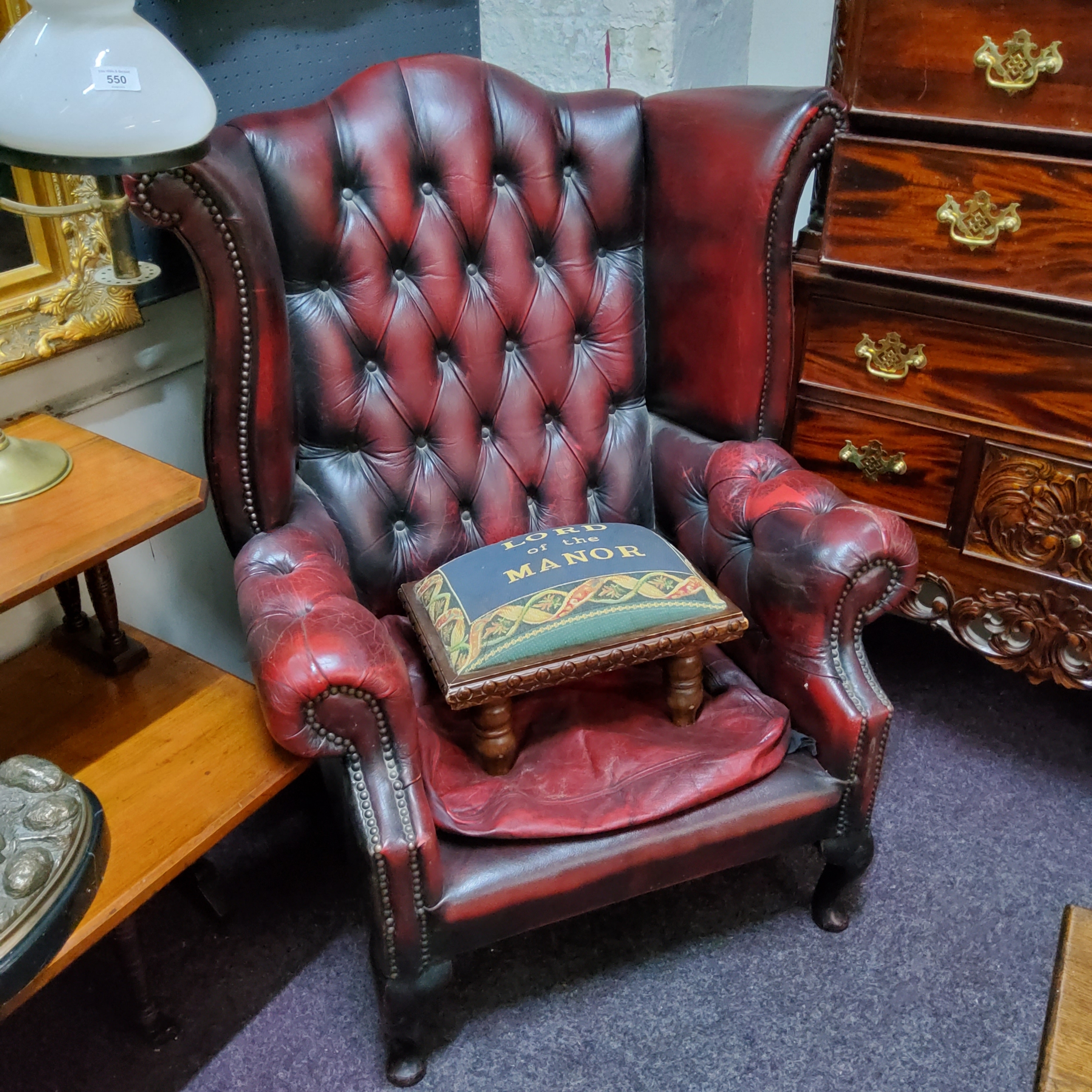 An ox blood red leather Chesterfield wingback armchair, deep button backed; Lord Of The Manor