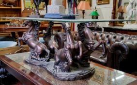 A decorative bronzed resin and toughened glass coffee table raised on rampant Marley horse