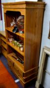 A modern freestanding open bookcase, two fixed shelves above two short above one long drawer to