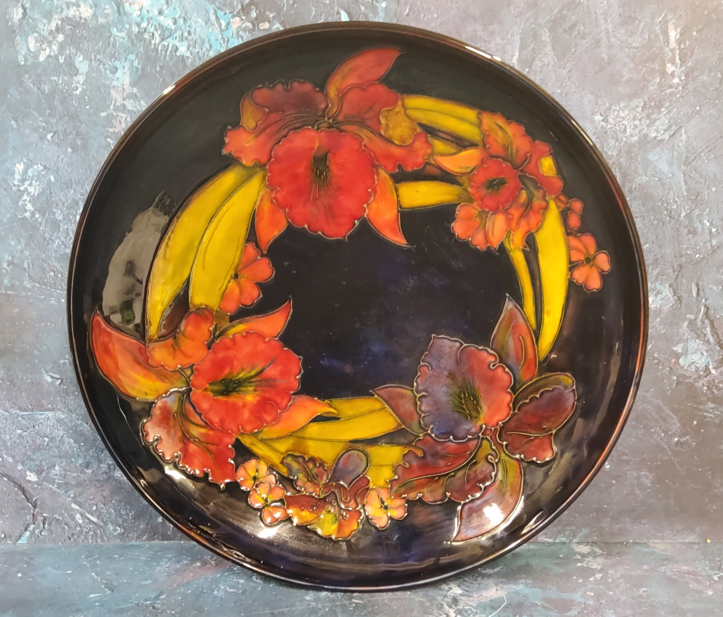 A Moorcroft Flambe Orchid pattern circular bowl, tube lined with flowers and leaves, in tones of red