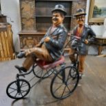 A Laurel and Hardy riding on a four wheel metal bike