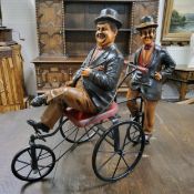 A Laurel and Hardy riding on a four wheel metal bike