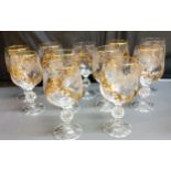 A set of eleven wine glasses, each applied in relief in gilt with scrolls, 15.5cm high