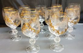 A set of eleven wine glasses, each applied in relief in gilt with scrolls, 15.5cm high