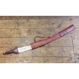 A large South African tribal sword in embossed red leather sheath, the curved blade etched with