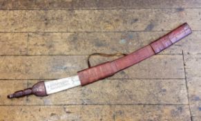 A large South African tribal sword in embossed red leather sheath, the curved blade etched with