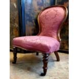 A Victorian nursing chair in a rich pink damask upholstery c.1860, brass castors