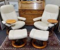 A pair of cream leather Ekornes Stressless armchairs with matching footstools.