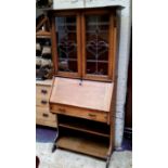 An Arts & Crafts oak bureau bookcase with oversailing cornice, sinuous stained glass leaded panel