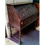 A late 19th / early 20th century carved padouk wood scholar's bureau on stand, profusely carved with