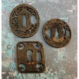 A Japanese iron tsuba, oval, pierced with blossoming prunus, 4.5cm wide;  others (3)