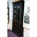 A tall Victorian ebonised display cabinet, comprising of heavily carved with masks, scrolls and