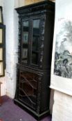 A tall Victorian ebonised display cabinet, comprising of heavily carved with masks, scrolls and