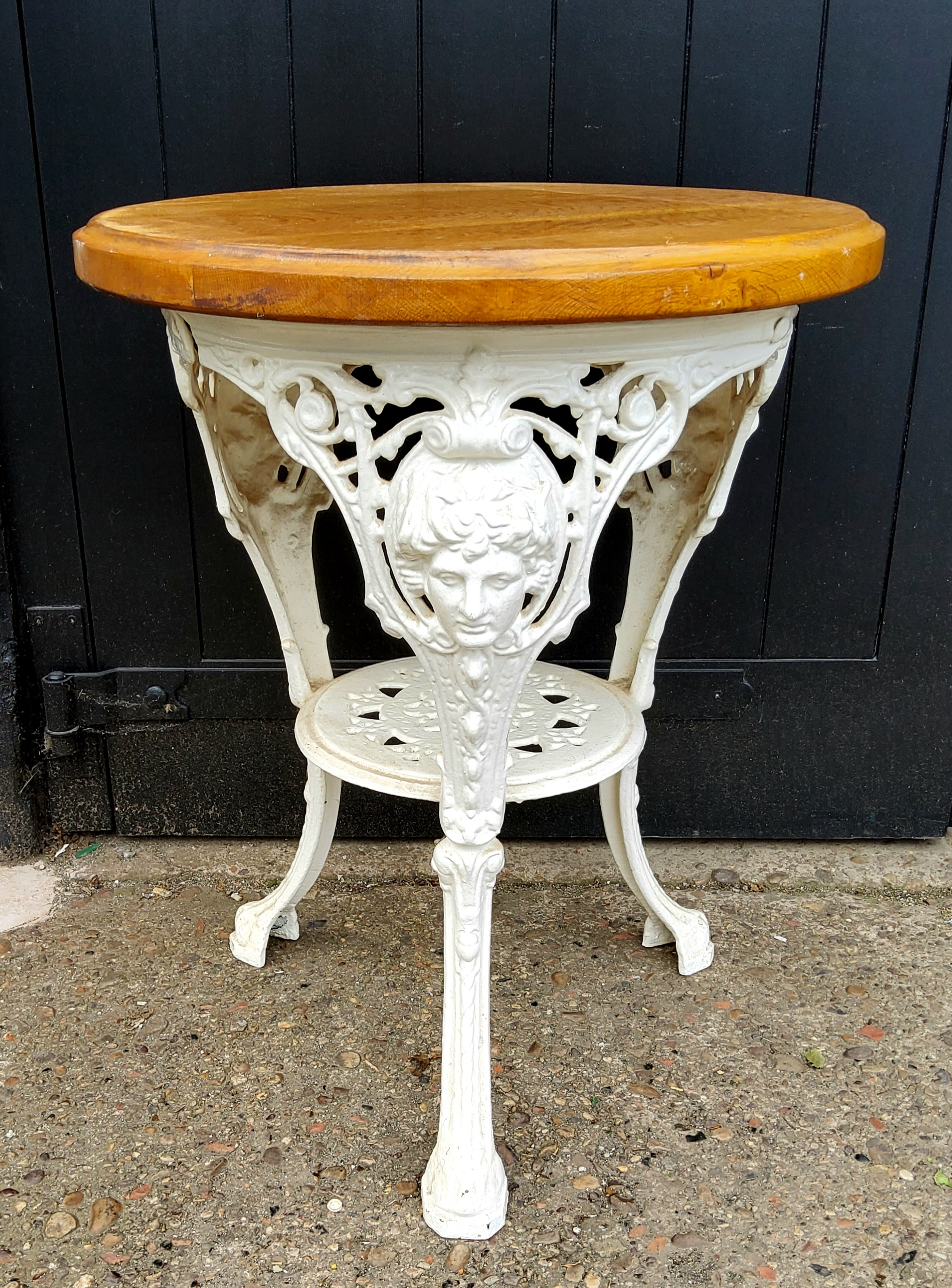 A Victorian cast iron pub table, bold mask capped trio with pierced circular under tier, later